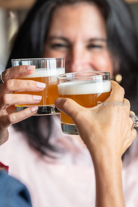 微笑的成熟女人用啤酒敬酒