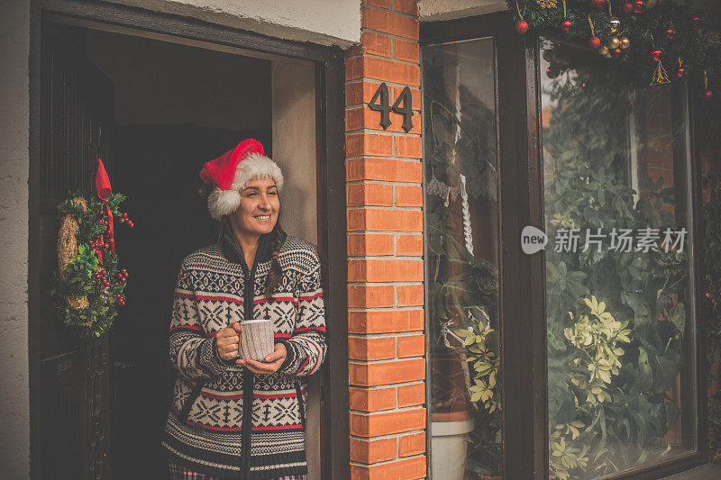 戴圣诞老人帽的女人在她家门口喝茶