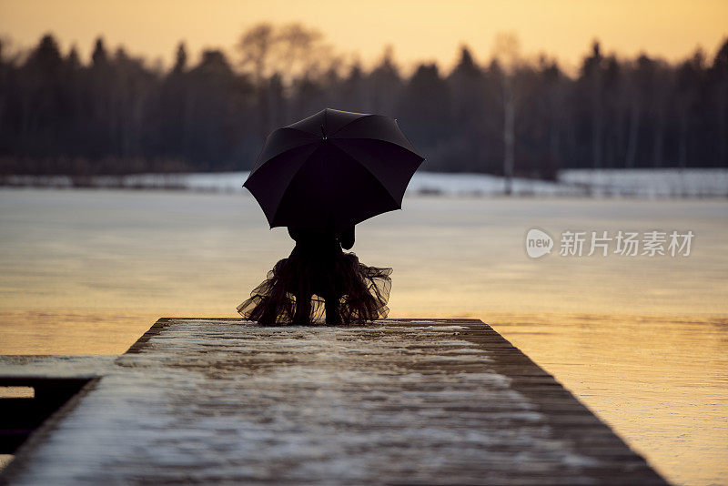 美丽的女人在冰湖边打着伞