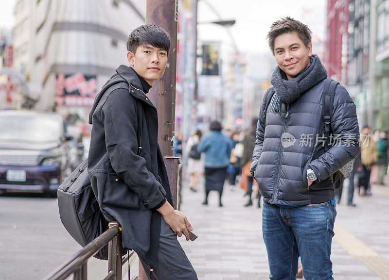 年轻的亚洲男子和日本朋友寻找旅游地点使用手机和花时间在亚洲旅行