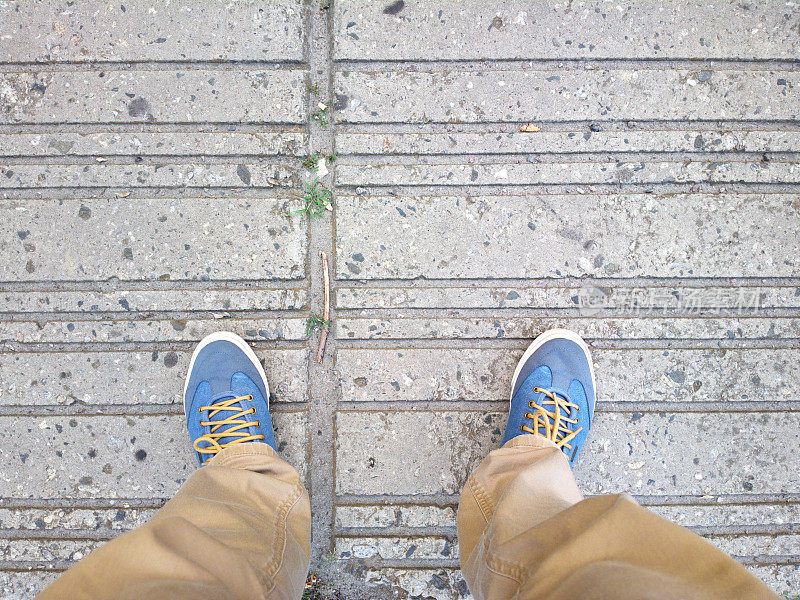 双脚踩在沥青上。腿在瓷砖上。