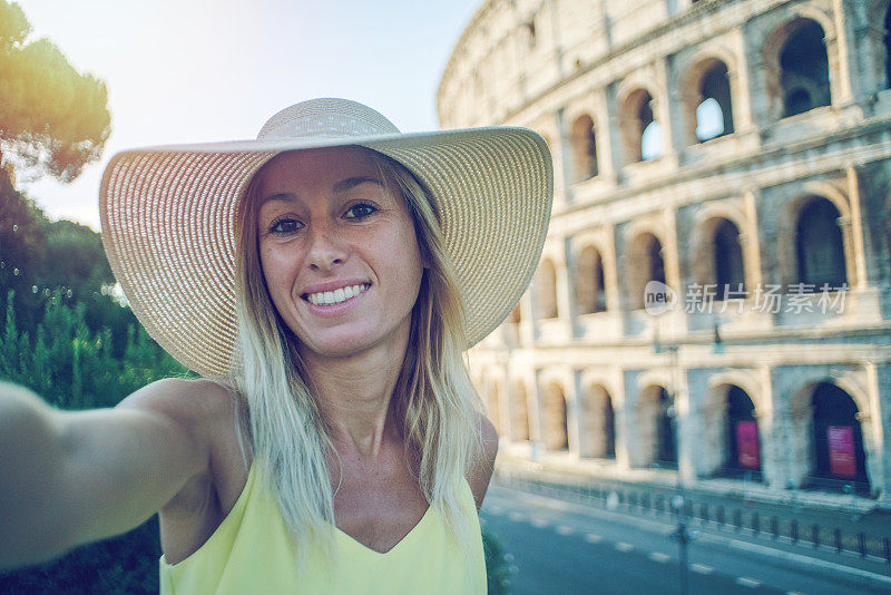 一名年轻女子在罗马享受意大利旅行的自拍，并在著名的罗马斗牛场前拍摄了一张照片