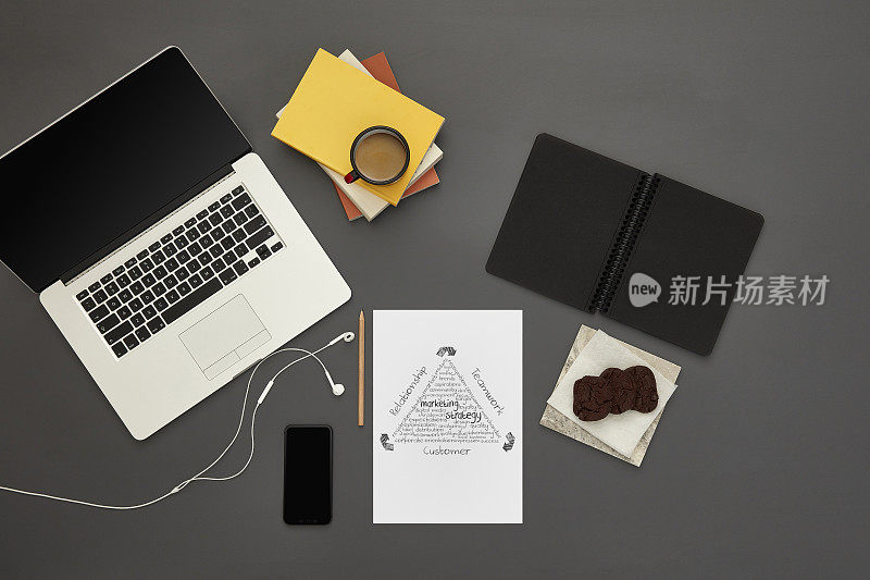 工作桌顶视图与笔记本电脑和营销词在纸上。
