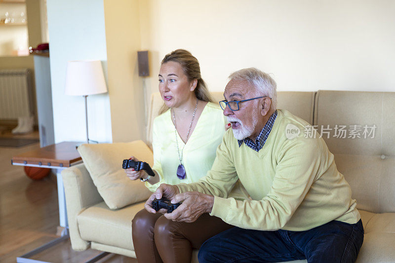 英俊的老男人和他成熟的女儿一起在家玩游戏机。