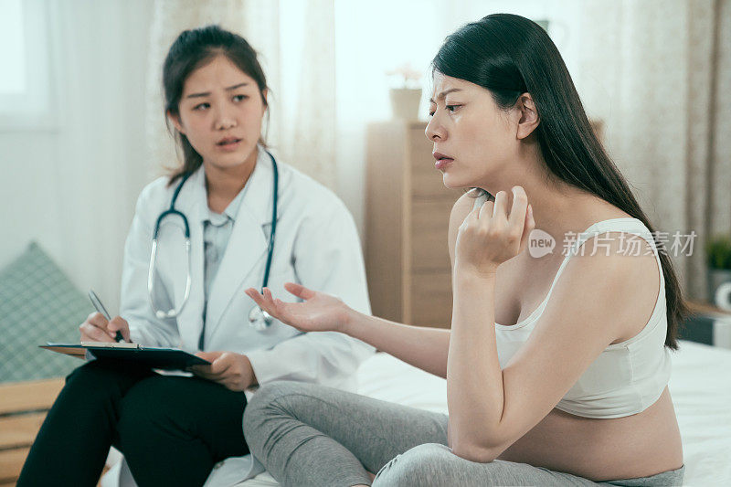 病床上，医生坐在悲伤的孕妇旁边