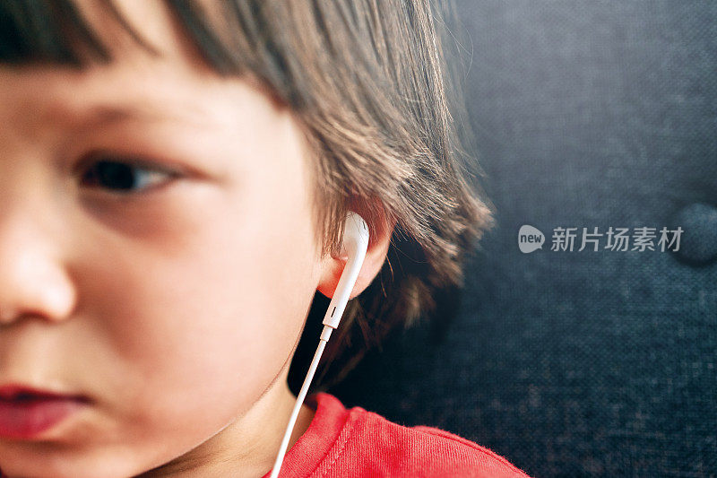 4-5岁的孩子用智能手机耳机听东西。