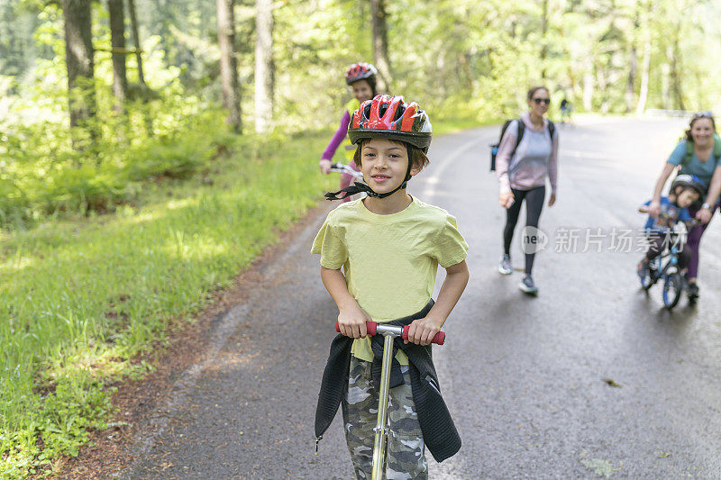 孩子们和他们的妈妈在乡村公路上骑自行车