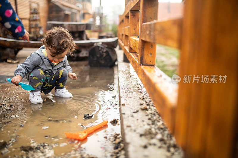 秋日雨后，小男孩在水坑里玩水