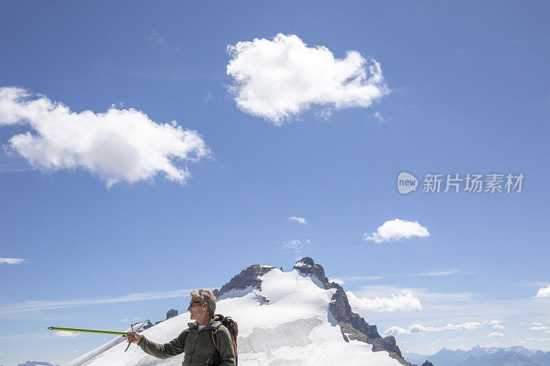 一位男性登山运动员到达了雪山的顶峰