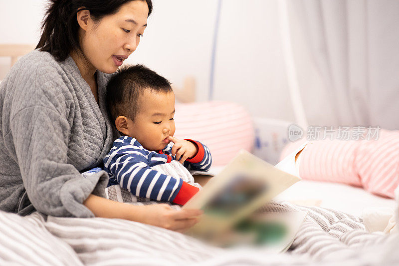 家人睡觉。妈妈和儿子在看图画书