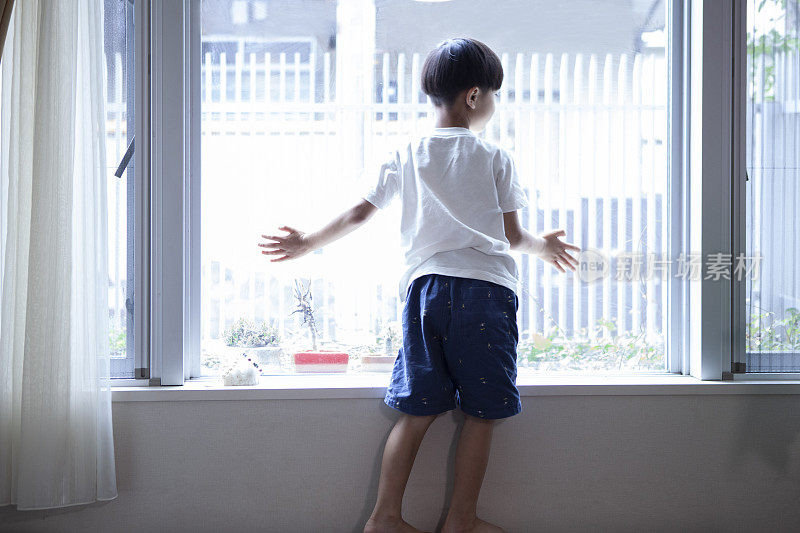 从房子的窗户往外看的男孩