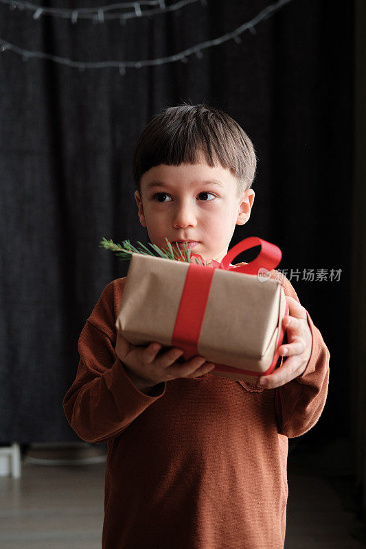 4-5岁的孩子拿着礼物盒在黑暗的背景为圣诞节庆祝