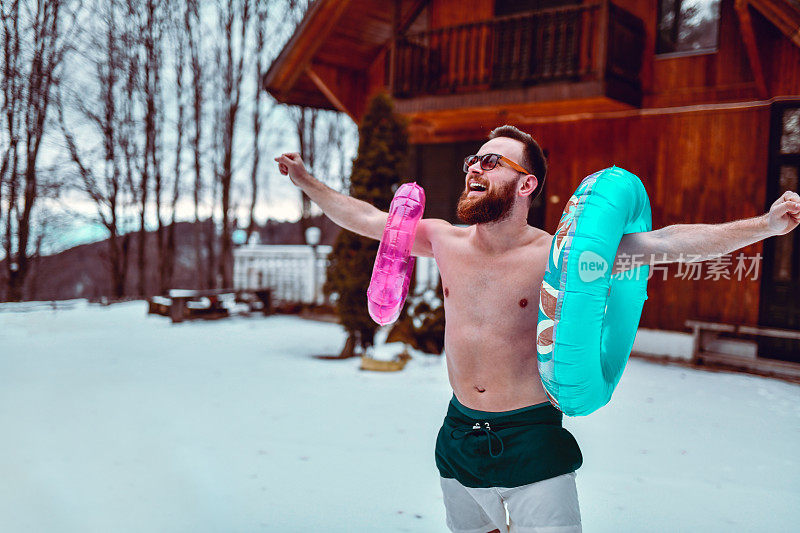 男性穿着短裤玩在山上的雪充气环