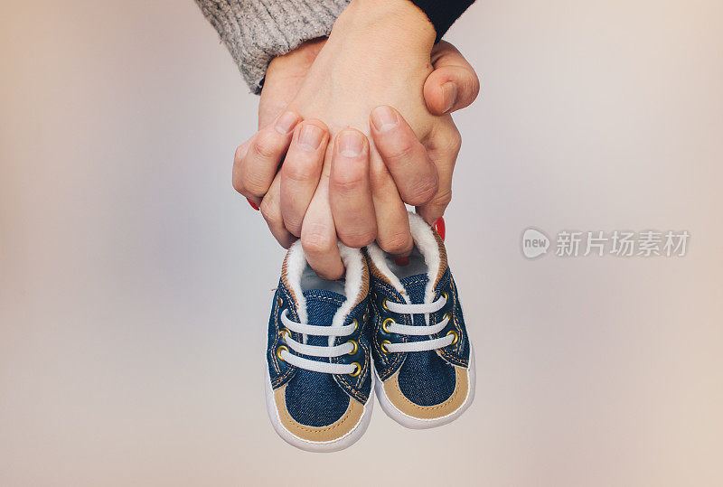 未来的父母抱着一双小鞋子的照片