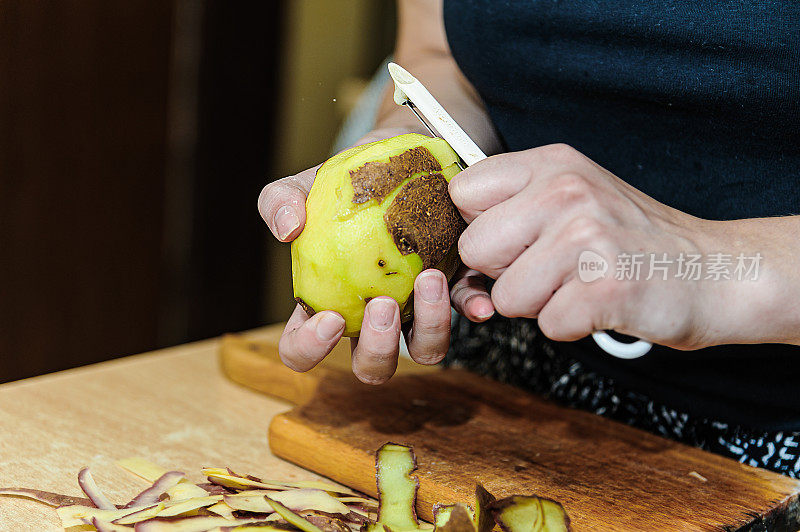 女厨师与厨房刀谁是削土豆和准备一顿美味的晚餐的特写视图。