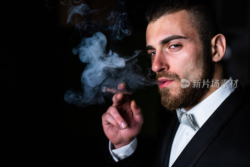 吐出雪茄烟雾的英俊男子