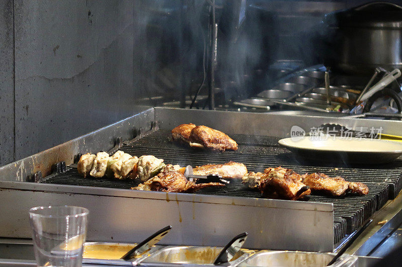 在商业烤架上烹饪街头食品的图像，在金属烤架上烹饪烤鸡块