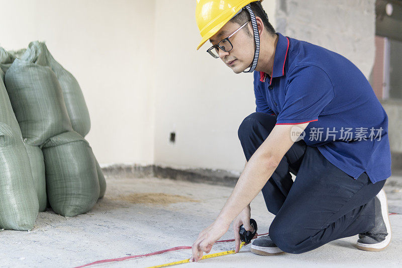 亚洲男工程师在翻新工地戴着头盔工作