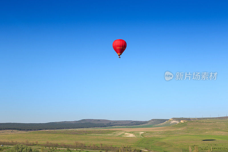 一张气球在山谷上空飞行的照片。今天是乘坐热气球飞行的好天气，鸟瞰山谷和群山的美丽全景