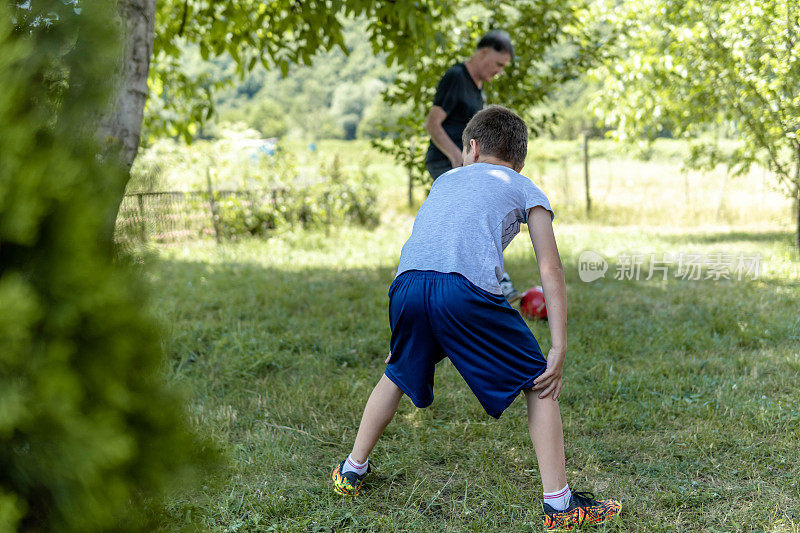 活跃的高级足球或足球运动员与孙子在后院玩