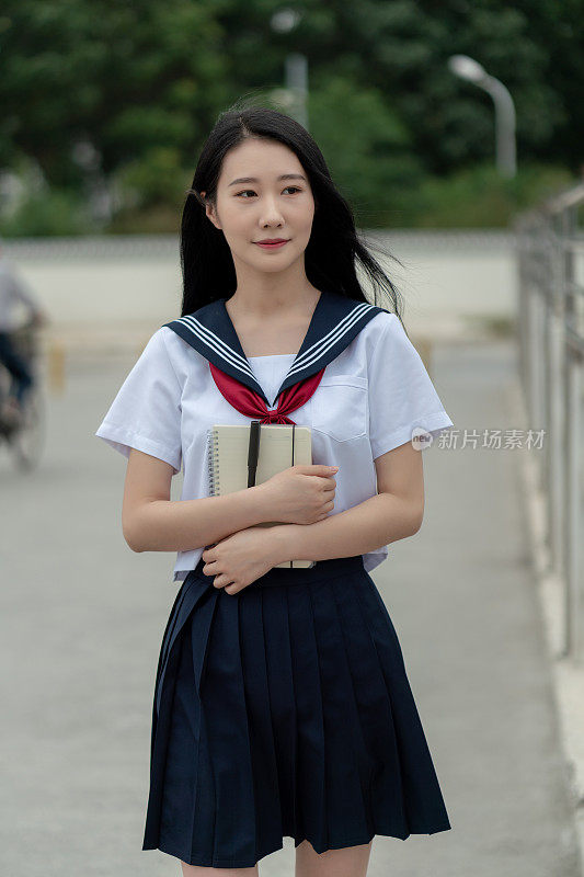 年轻的亚洲女性穿着学生服装，在大学里