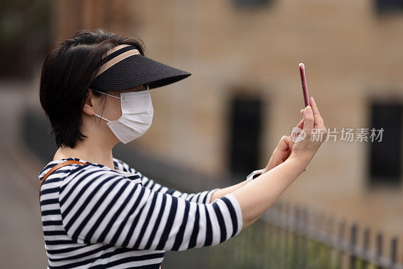 戴着口罩的女人用手机拍照