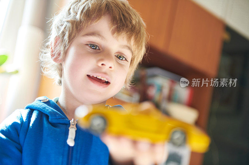 一个活泼的学龄前儿童在隔离期间玩玩具车的肖像