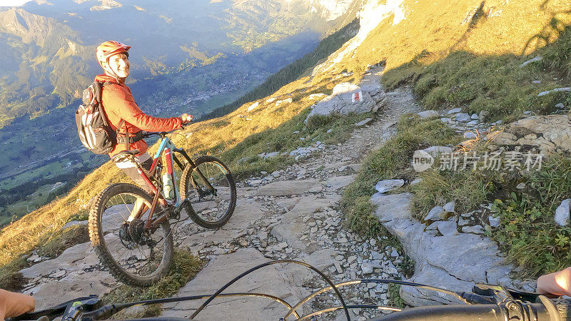 在阿尔卑斯山脉，一名男子推着山地自行车手沿着小路行进