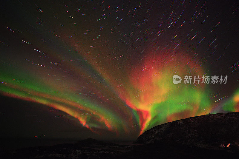 夜空中五颜六色的北极光。星星在山的轮廓上留下痕迹。数字化图像