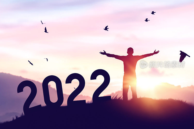 人在夕阳的天空举起手，鸟在山顶飞翔，数字像2022抽象的背景。