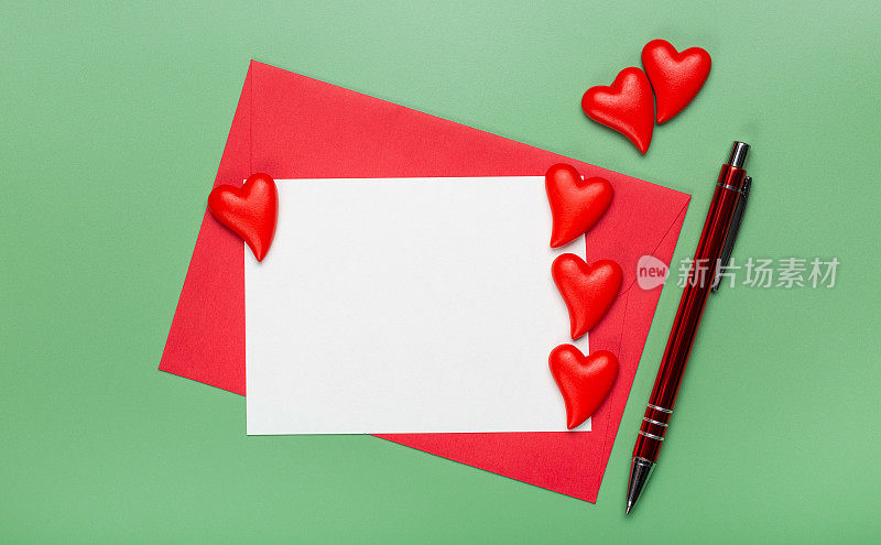 爱的概念。一张给心爱的人写信的白纸，一个红信封，许多美丽的心和一支笔