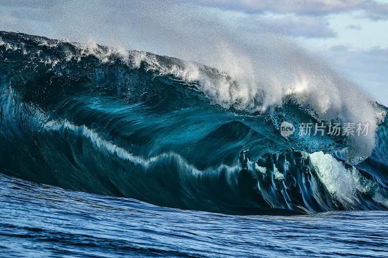极近距离细节强有力的青色蓝色波浪打破在浅层岩石边缘