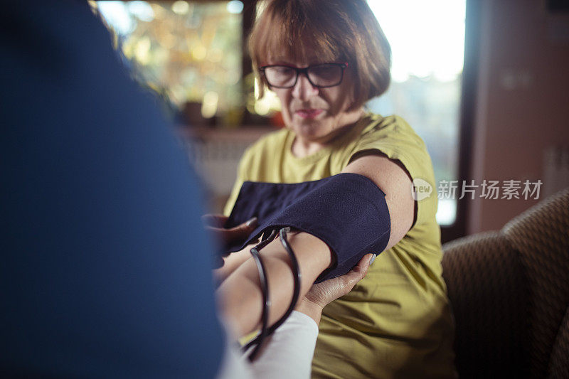 女医生在家给病人测血压。