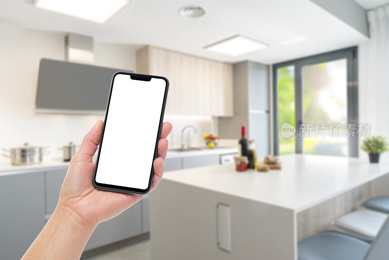 模糊的现代厨房中的手持智能手机与空白屏幕