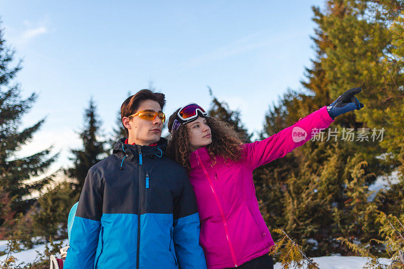 美丽的年轻异性恋夫妇在一个滑雪假期散步在自然而牵手