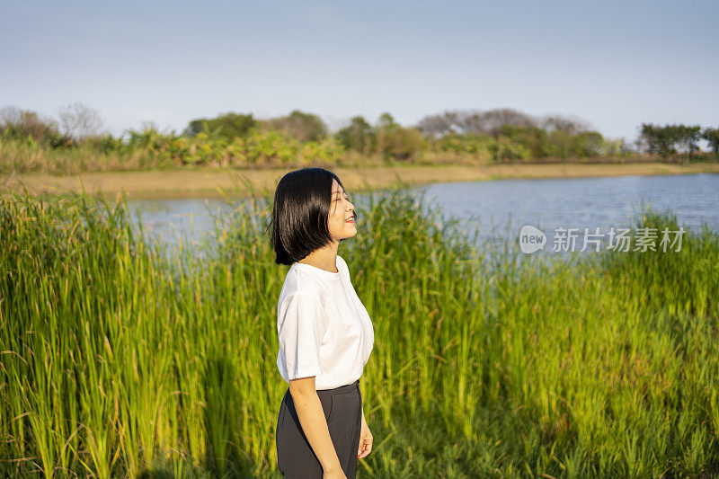 一位亚洲妇女在美丽的湖边眺望远方