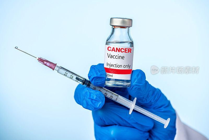 医生或护士拿着癌症疫苗，用她的蓝色手套注射。