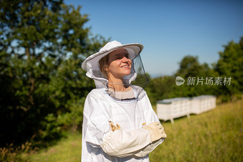 一名女性养蜂人在蜂箱前穿着防护服的肖像