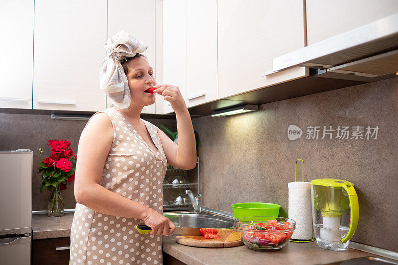 一位穿着棕色衣服的年轻女子在米黄色的厨房里做素食沙拉。