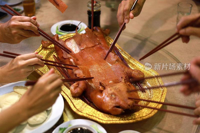 烤乳猪，人们用筷子吃饭