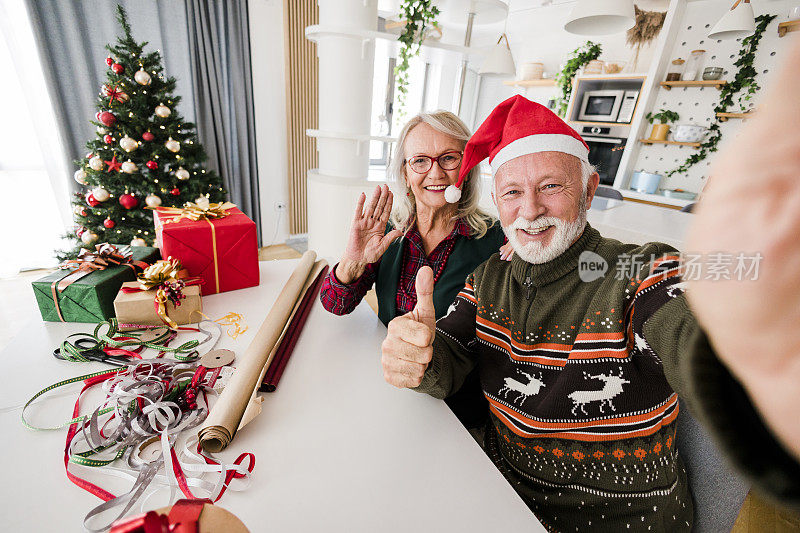 一对幸福的老夫妇在家一起包装圣诞礼物的自画像