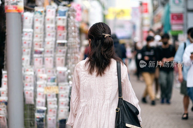 在原宿购物的女人的后视图