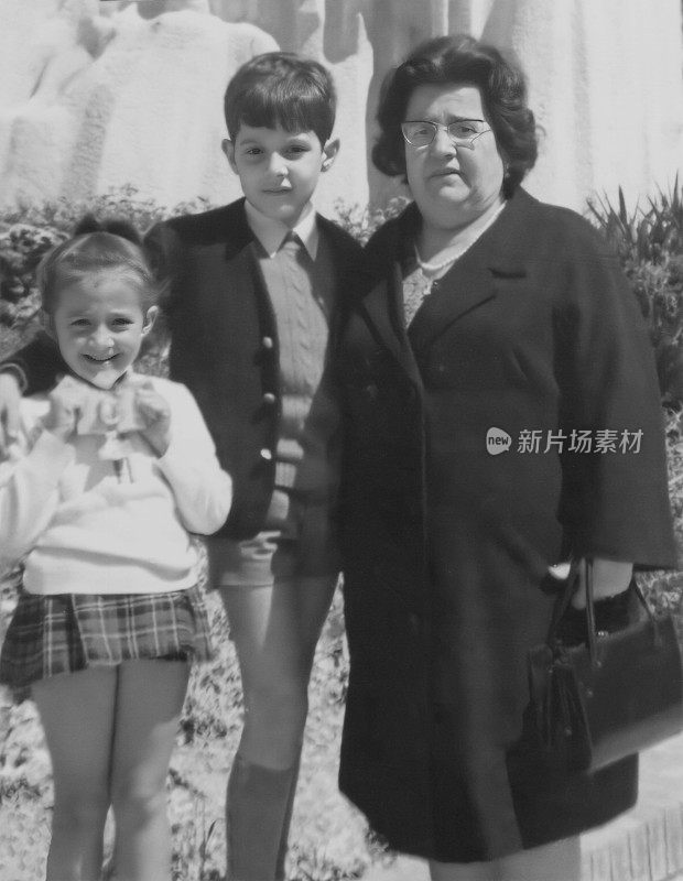 拍摄于60年代的照片:孩子们和他们的年长的成熟女人一起对着相机摆姿势