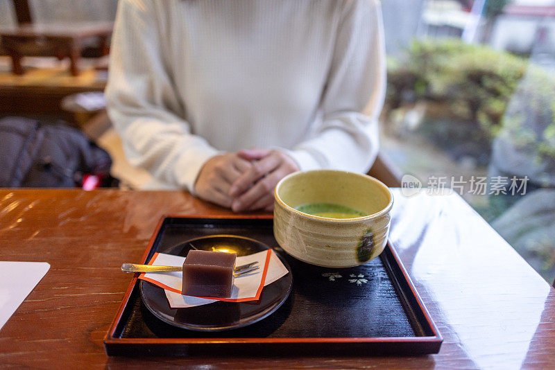 女人坐在榻榻米上，准备吃日式糖果和抹茶