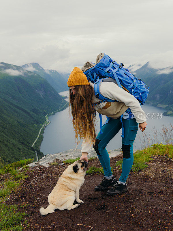 快乐的女人带着她的狗在挪威的山上徒步旅行