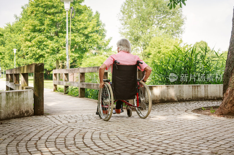 坐在轮椅上的老人，在公园里享受着一天