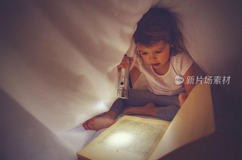 小女孩在黑暗中看书，被窝在床上