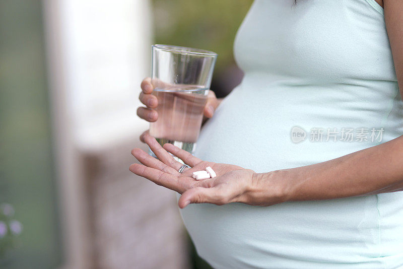 成年孕妇正要用水吞下维生素