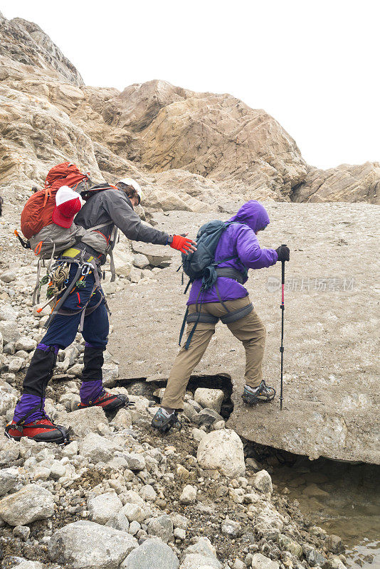 导游协助高级女性在冰冷的冰川上