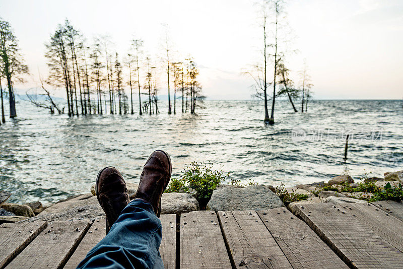 男人的脚在湖边穿鞋的特写